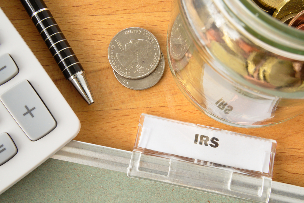 IRS file with calculator, pen, coins and glass jar