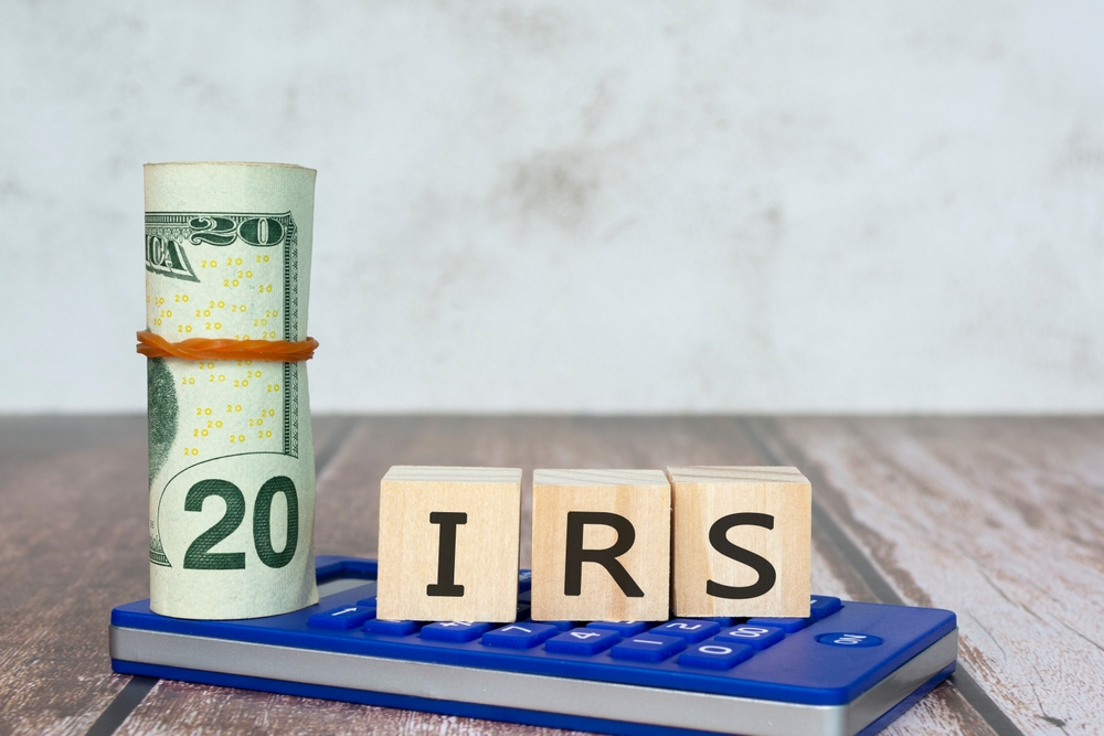 Internal Revenue Service On Wooden blocks with dollar bill and calculator on wooden table.